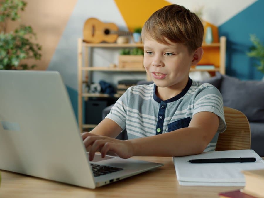 A young student focused on building something at their laptop